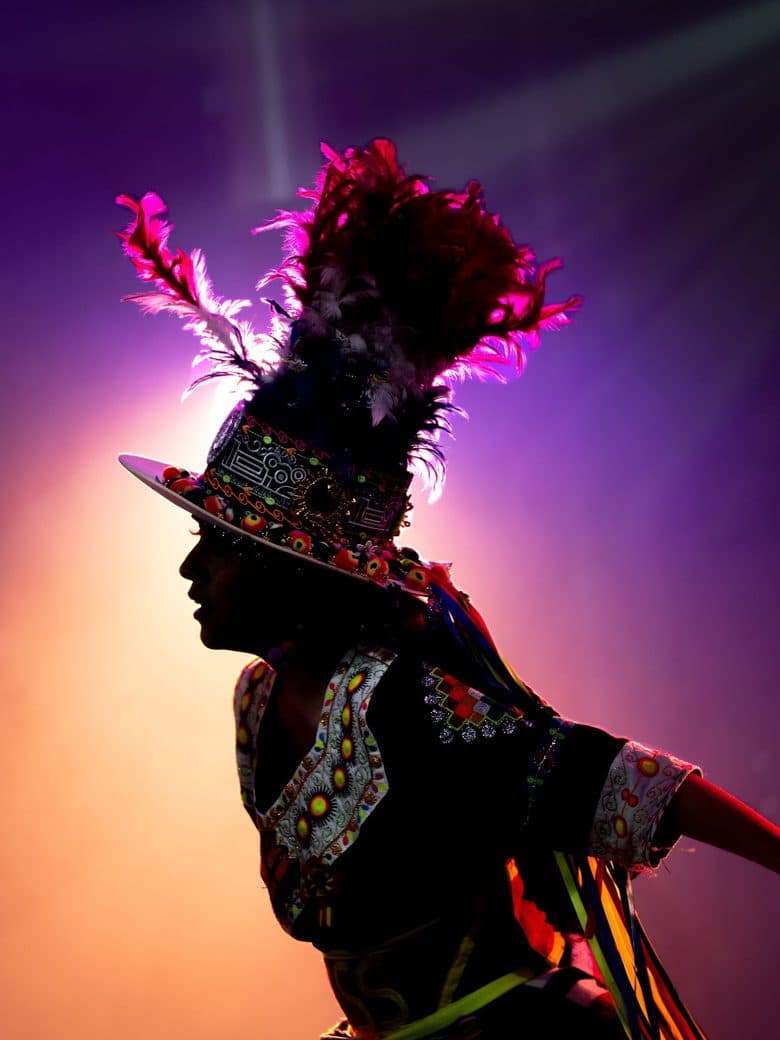 Carnival dancer in feathered costume against stage light