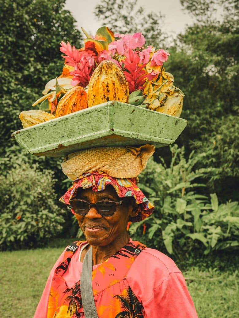 Island vendor carrying cocoa pods and tropical flowers