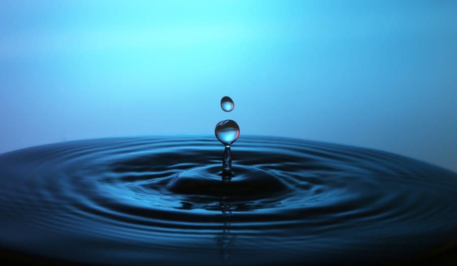 A water droplet rippling a deep blue surface