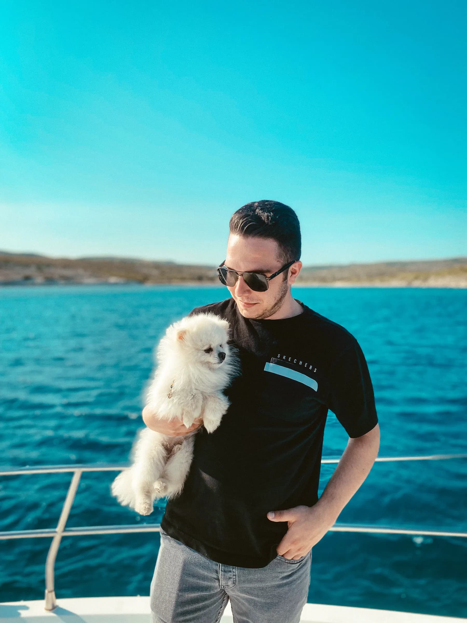 Guest holding a small dog on the deck of a yacht