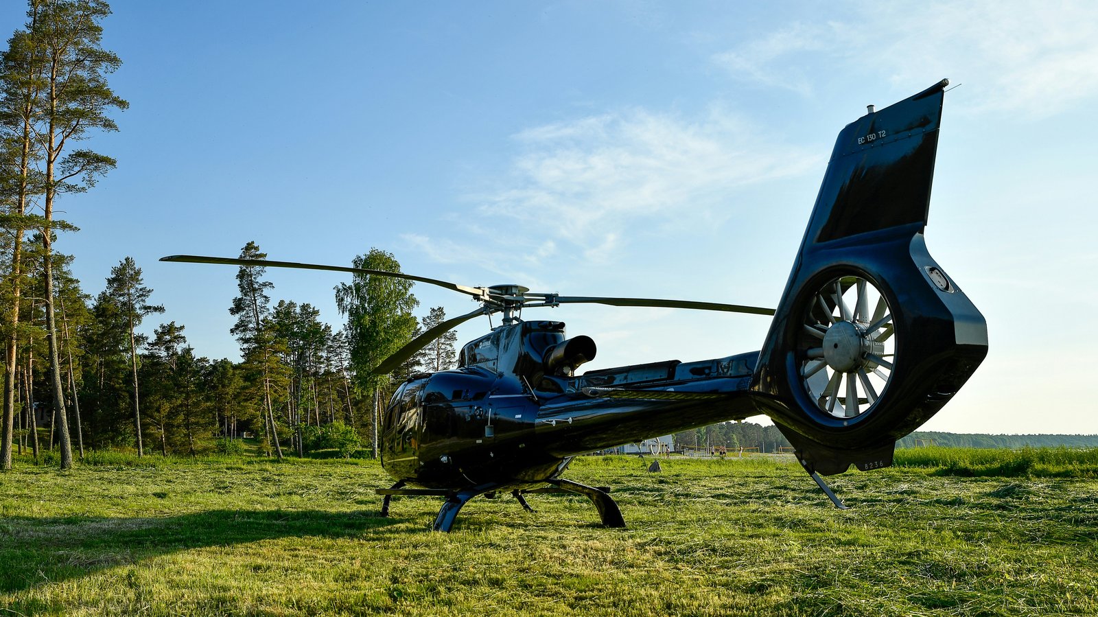 Private helicopter waiting on a meadow at golden hour